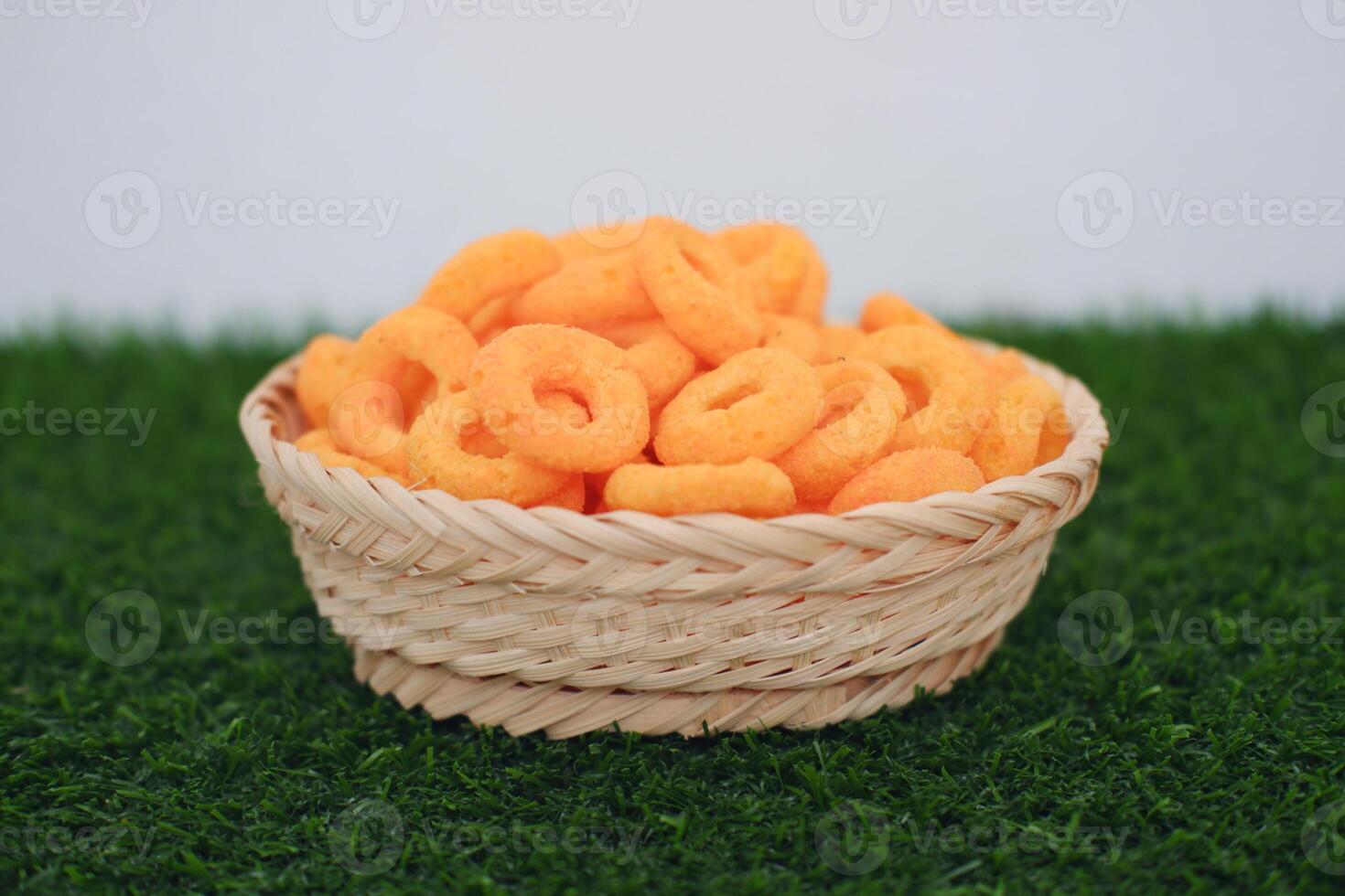 snack cheese crackers in a basket on green grass with white background. photo