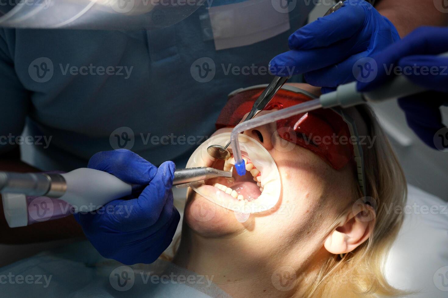 female dentist examining young girl patient's teeth at dental clinic. Doctor probing teeth with dental instrument using an explorer look for cavities treatment and checking problems with filling photo