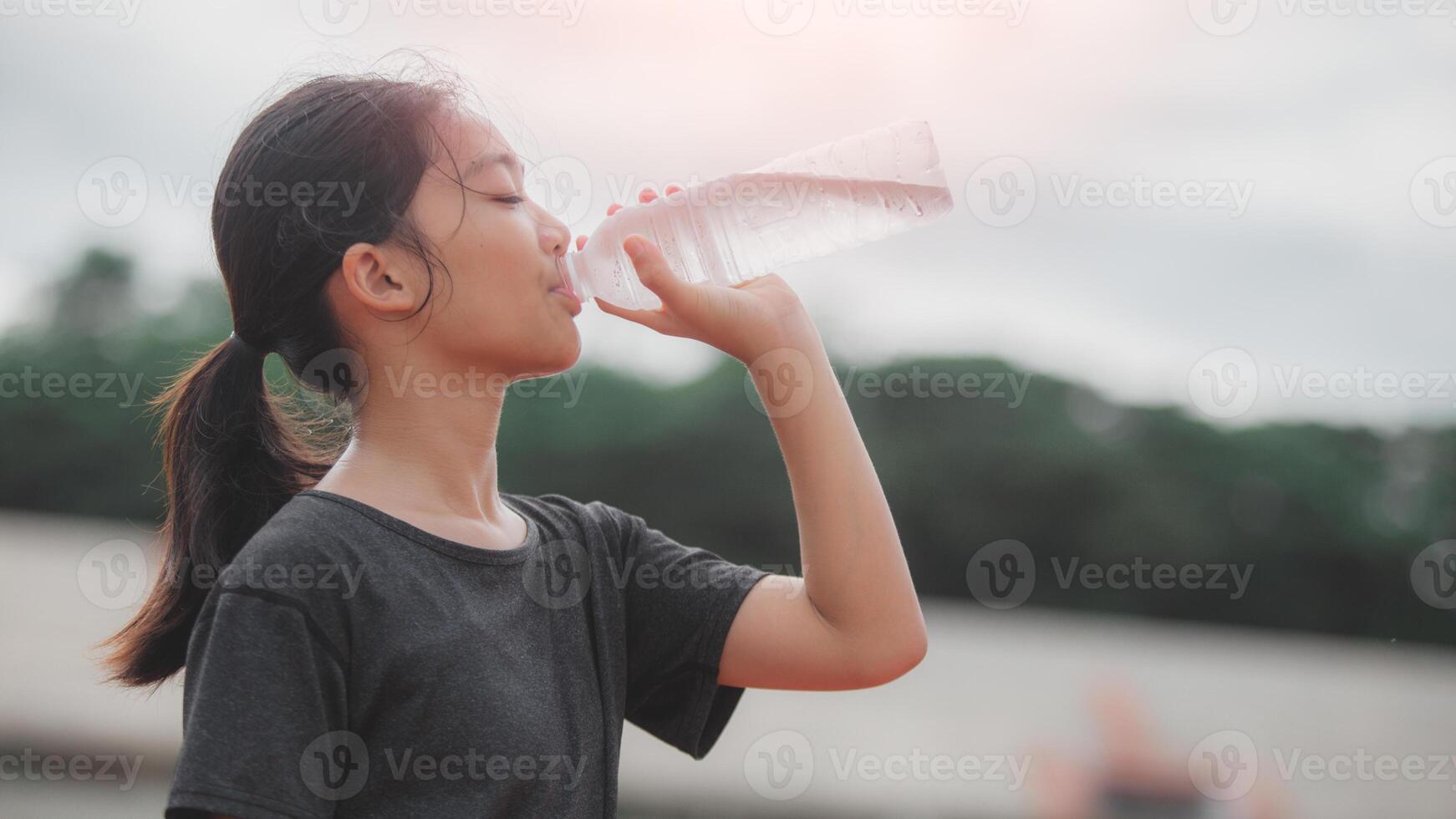 A girl drinking water from a bottle photo