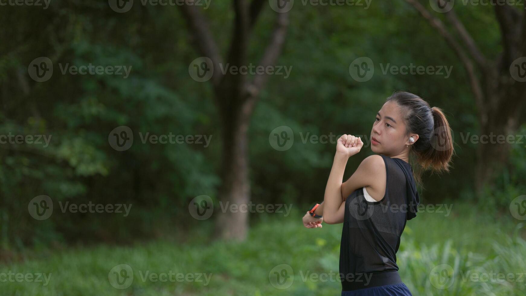 A woman is standing in a park, stretching her arms photo