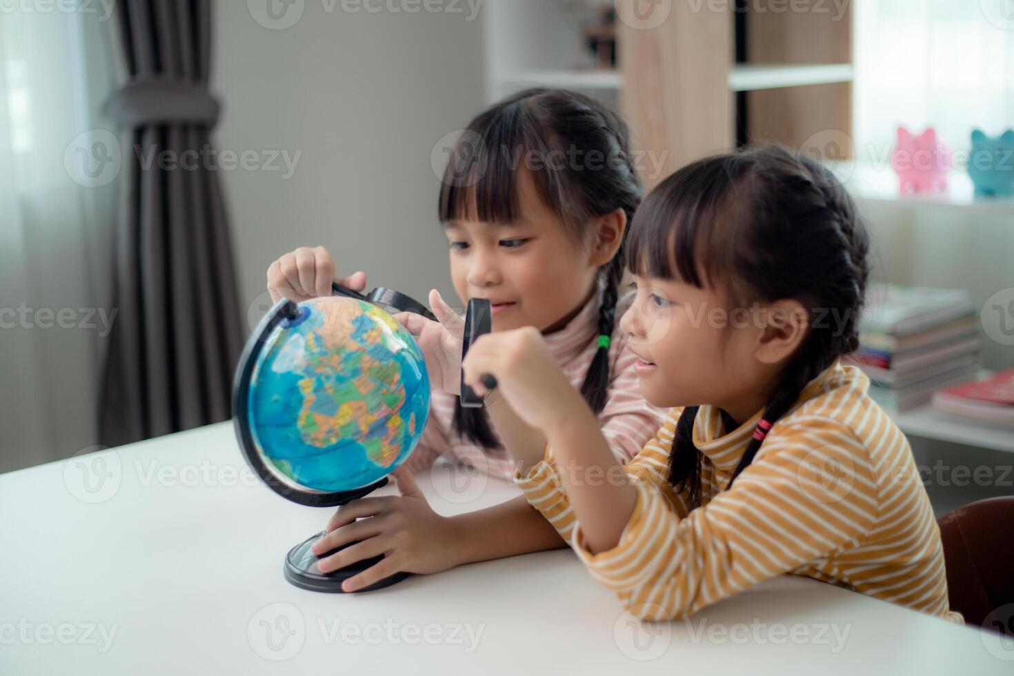 Two Asian little girl is learning the globe model, concept of save the world and learn through play activity for kid education at home. photo
