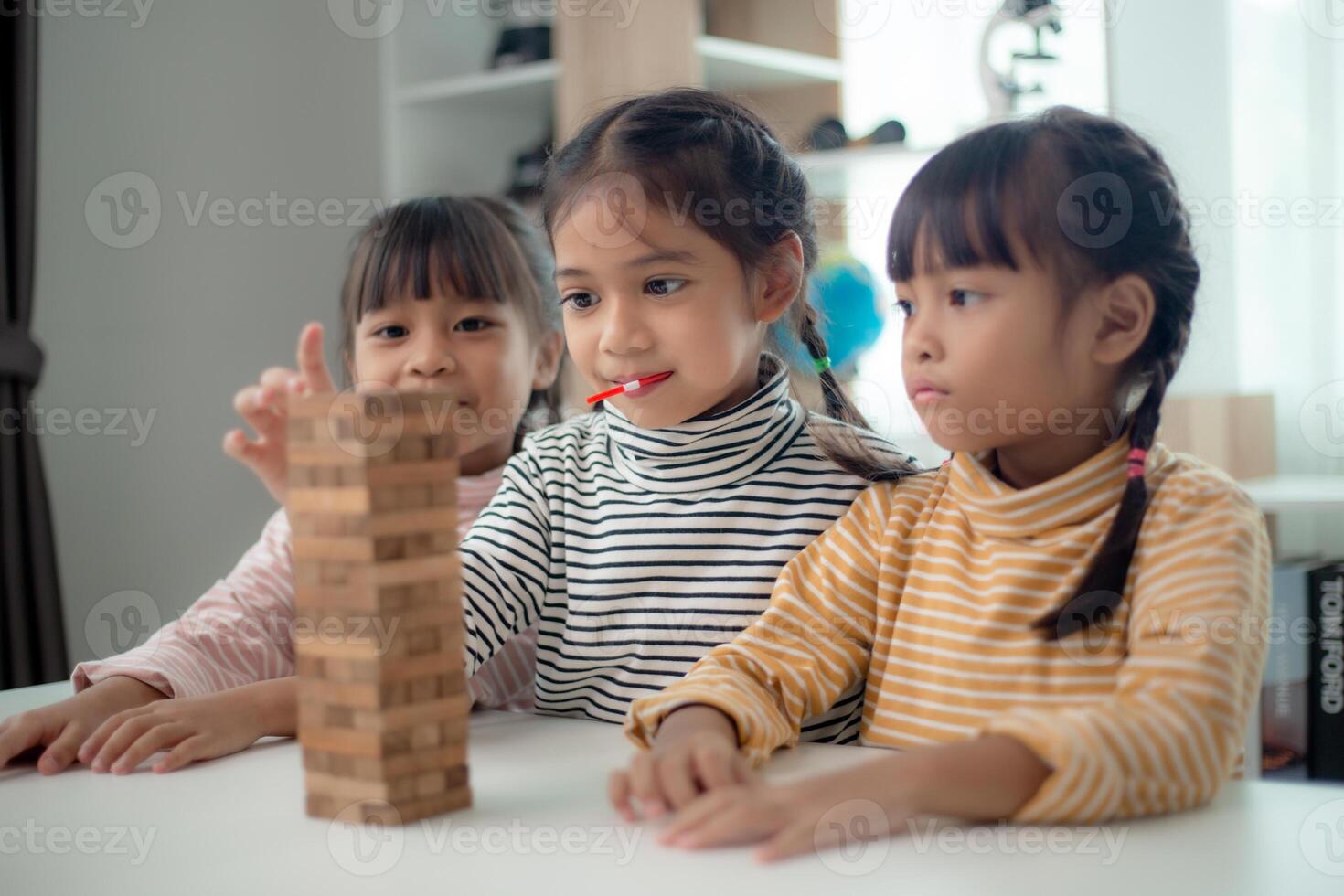 Three Asian girl is playing with wooden blocks on a table. photo
