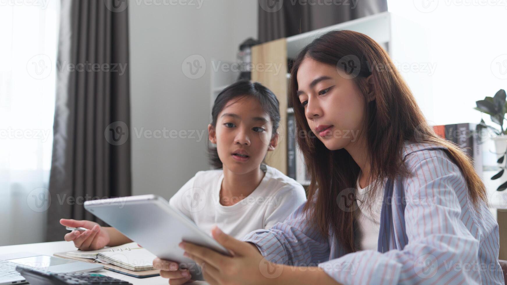 Asian siblings doing homework on a table at home photo