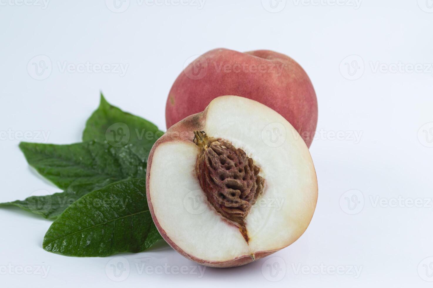 a peach with leaves and a slice cut in half photo