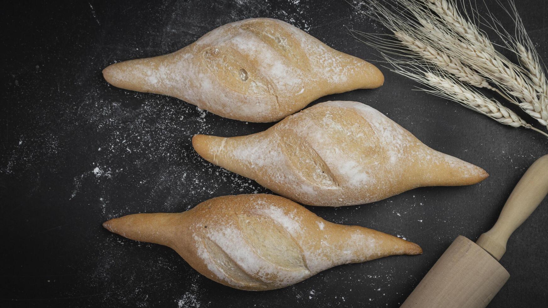 three buns with flour and wheat on a black background photo