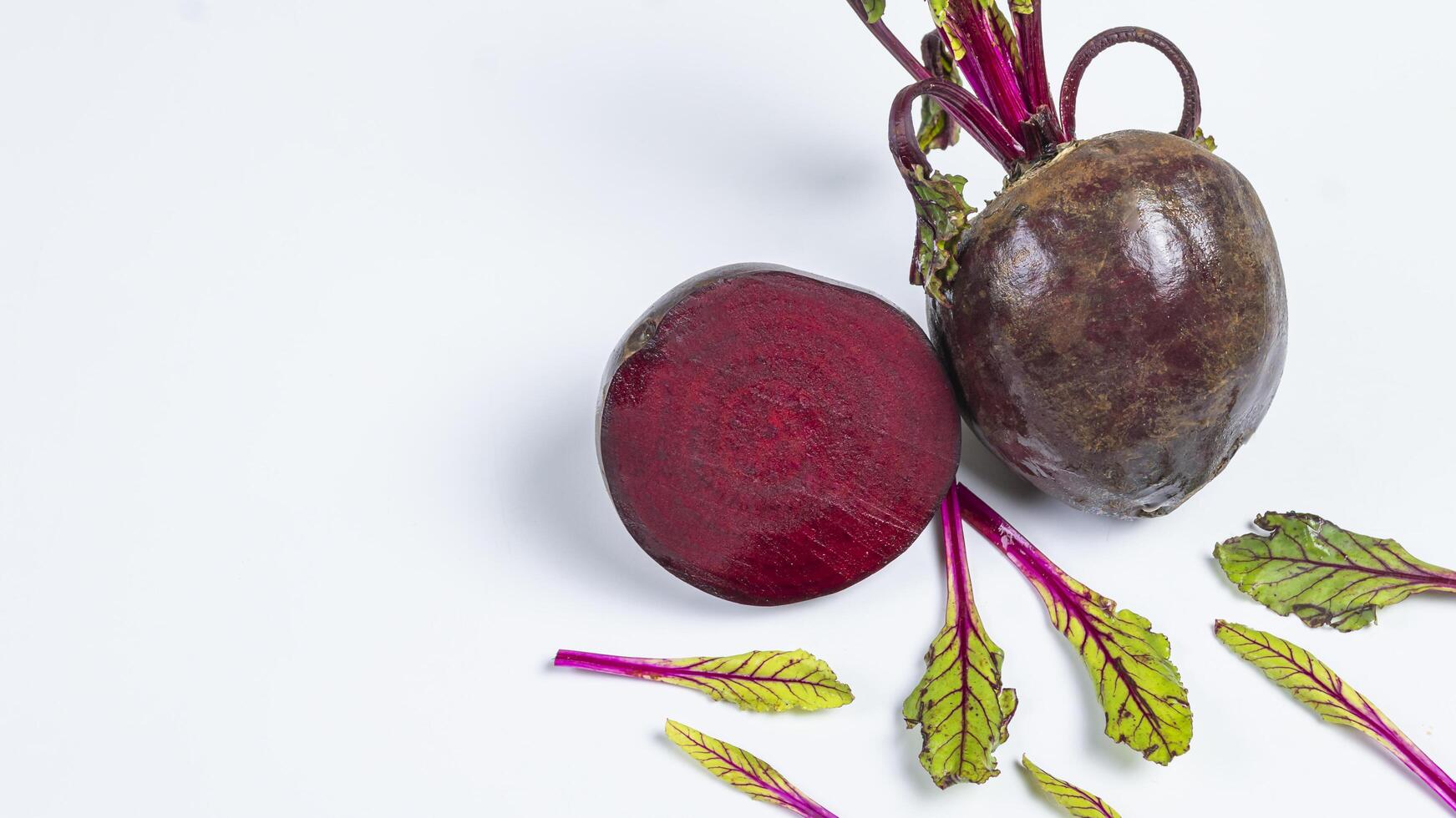 two beets on a white surface with leaves photo