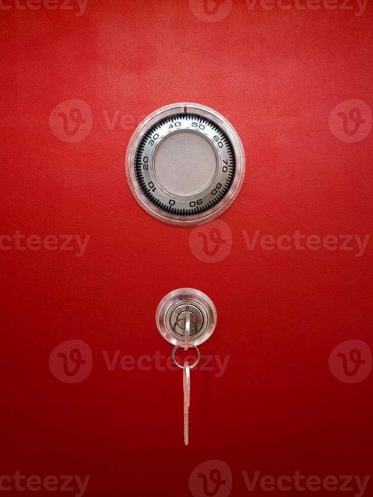 Red metal safe with combination lock and key. photo
