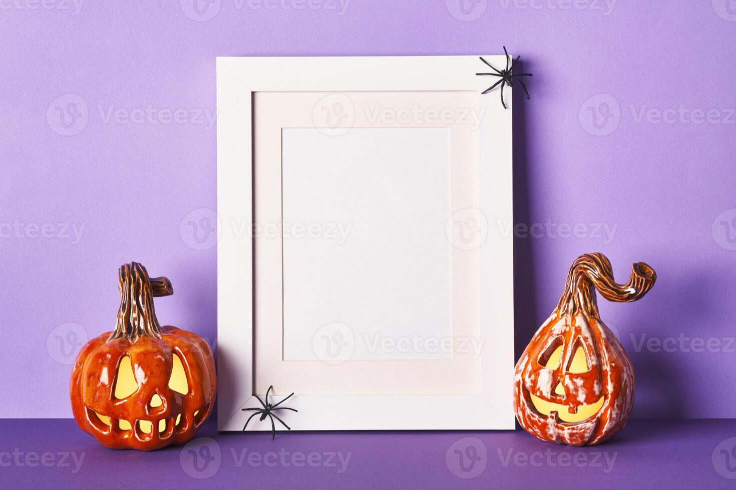 Halloween composition with ceramic pumpkins jack lantern and frame on table wall background. Greeting card template photo