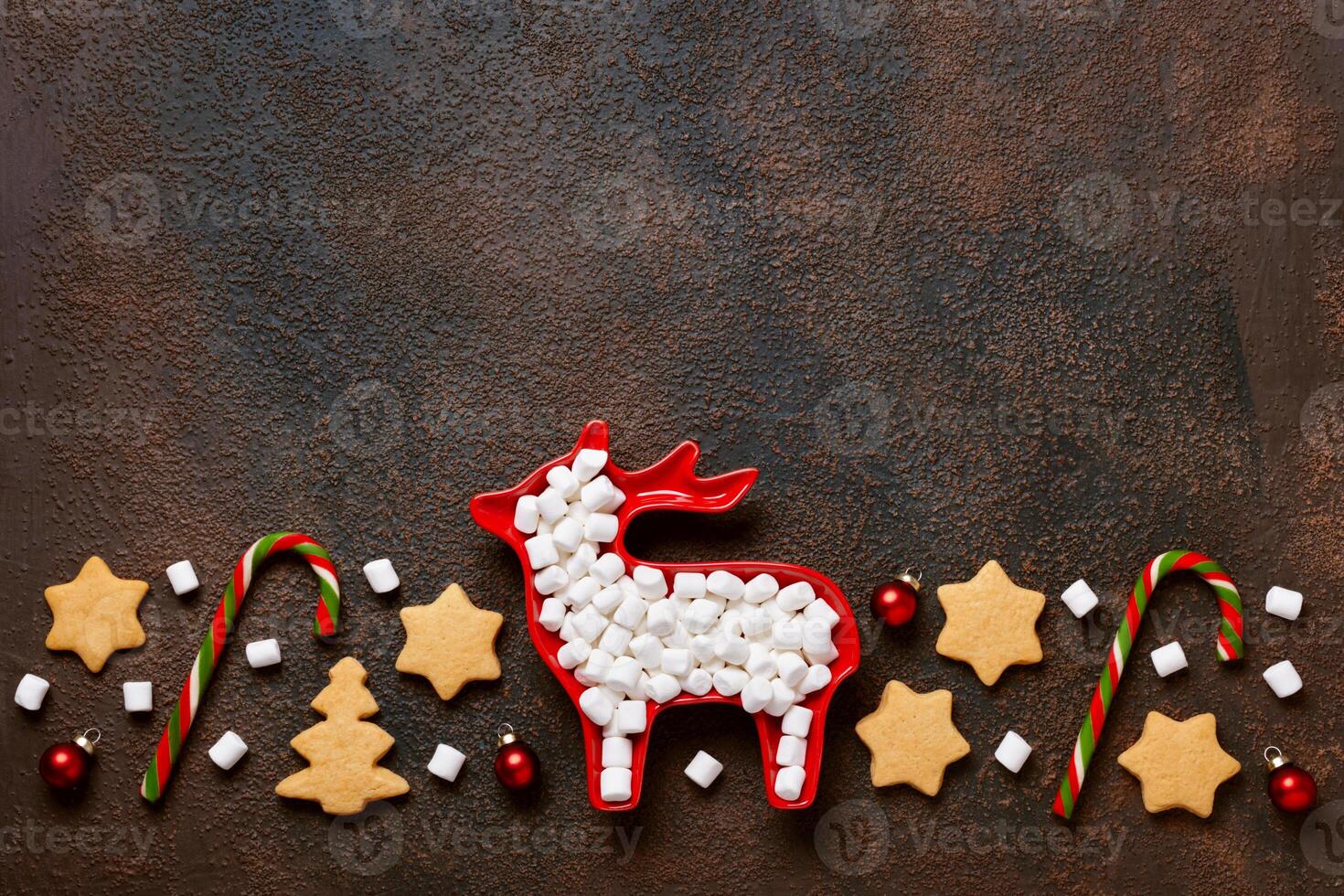 Christmas or New Year flat composition. Pattern from festive baubles, cookies and marshmallows on Brown background photo