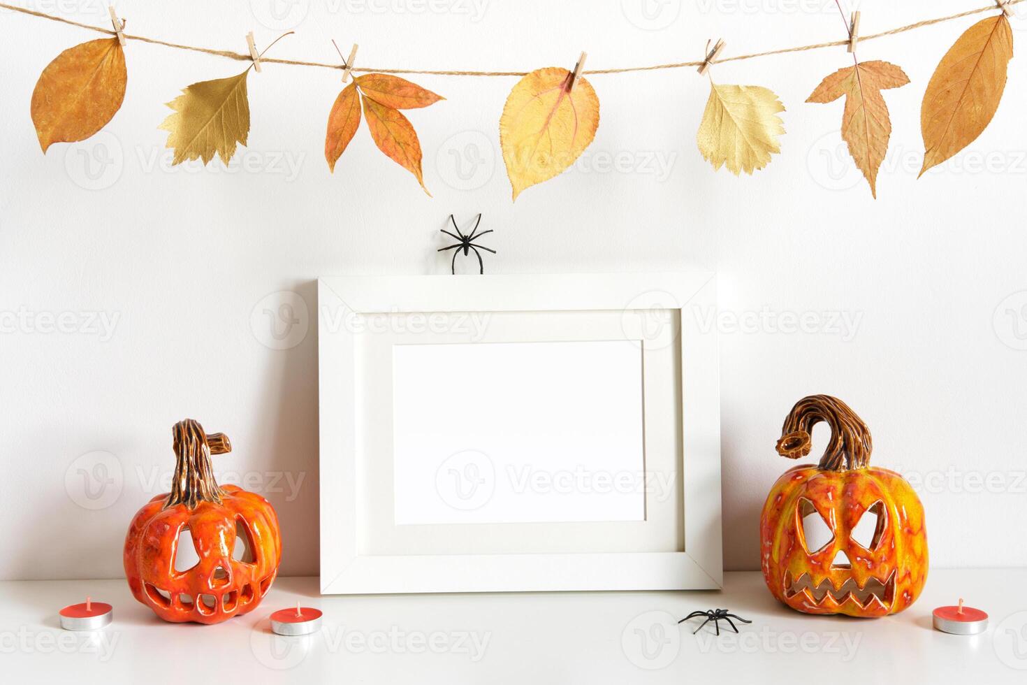 Halloween composition with ceramic pumpkins, floral garland and frame on table wall background. Greeting card template photo