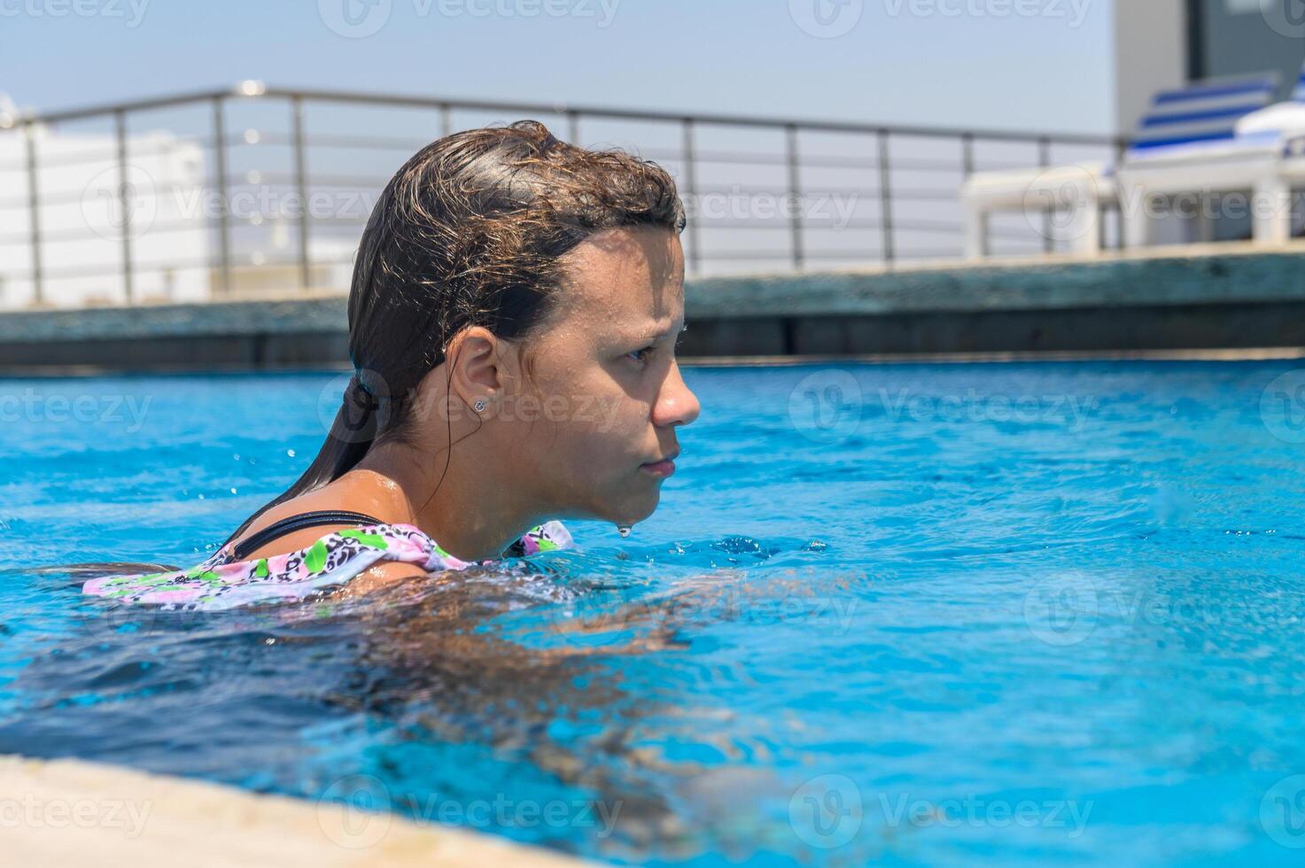A portrait of an 10 year old girl in an outside swimming pool photo