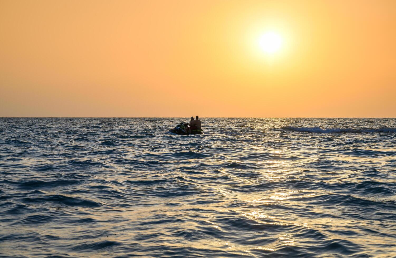 A man driving a jet ski , stunting and making spray of water drops with a sunlight on background photo