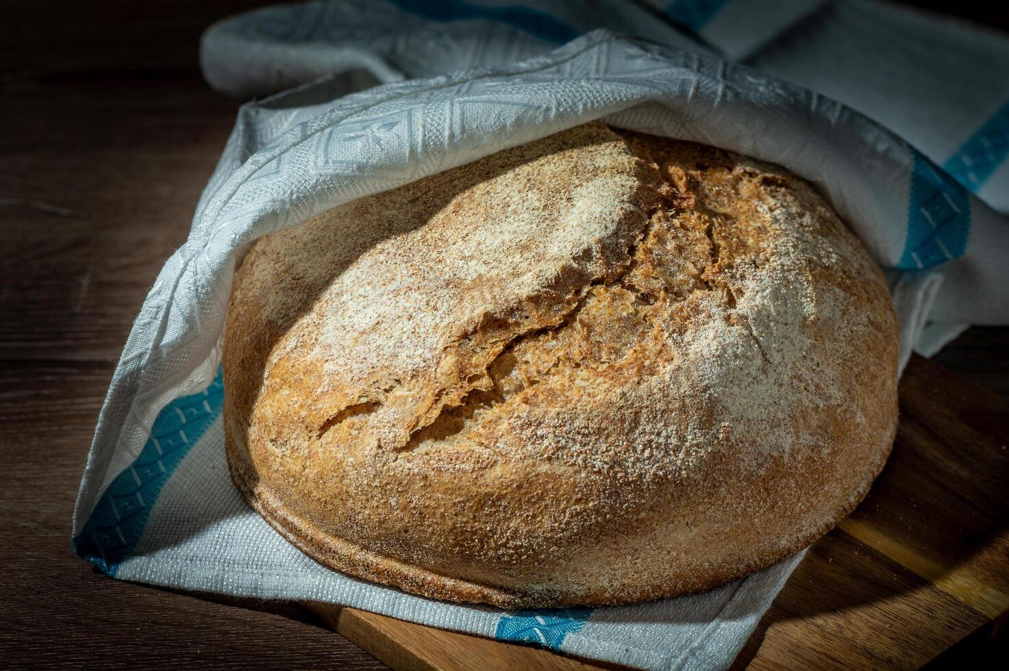 Freshly baked whole grain bread with slices on a wooden table photo