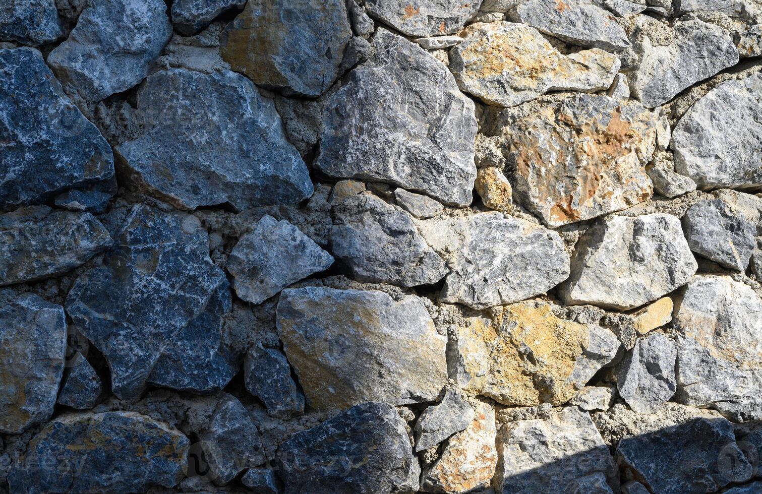 fence real stone wall surface with cement as background. photo