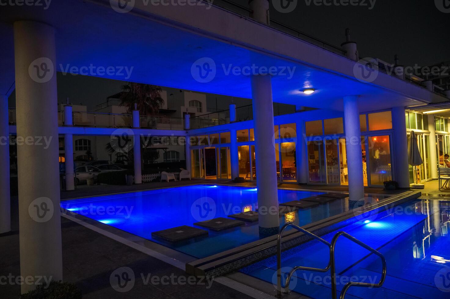 view of the night illuminated pool near with a residential complex resort photo