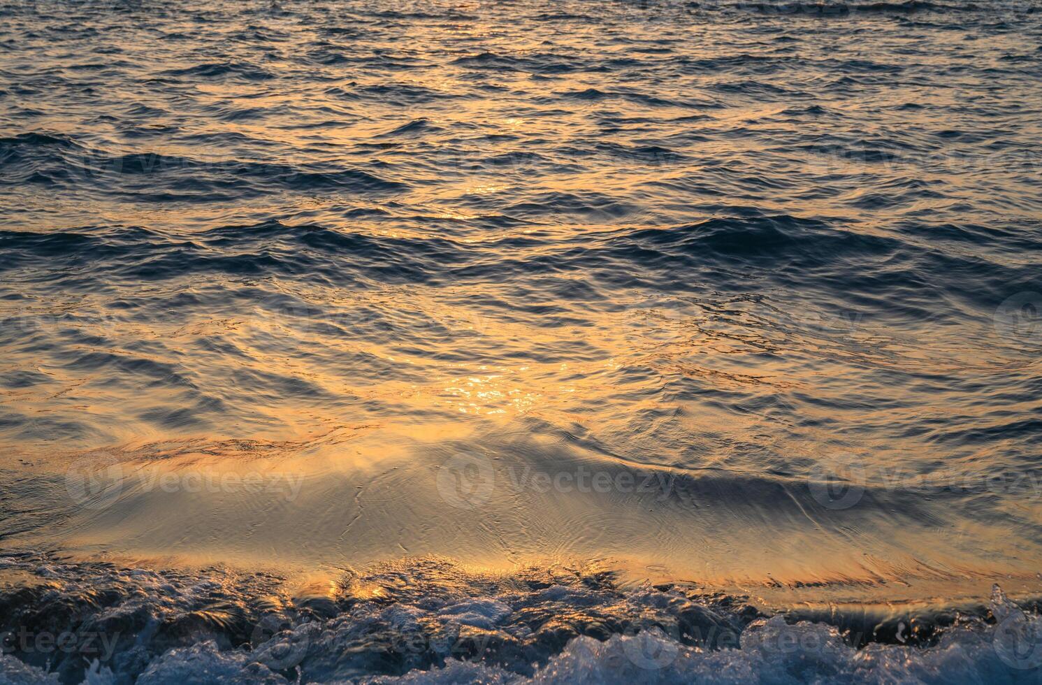 Abstract photo of surface water of sea or ocean at sunset time with golden light tone.