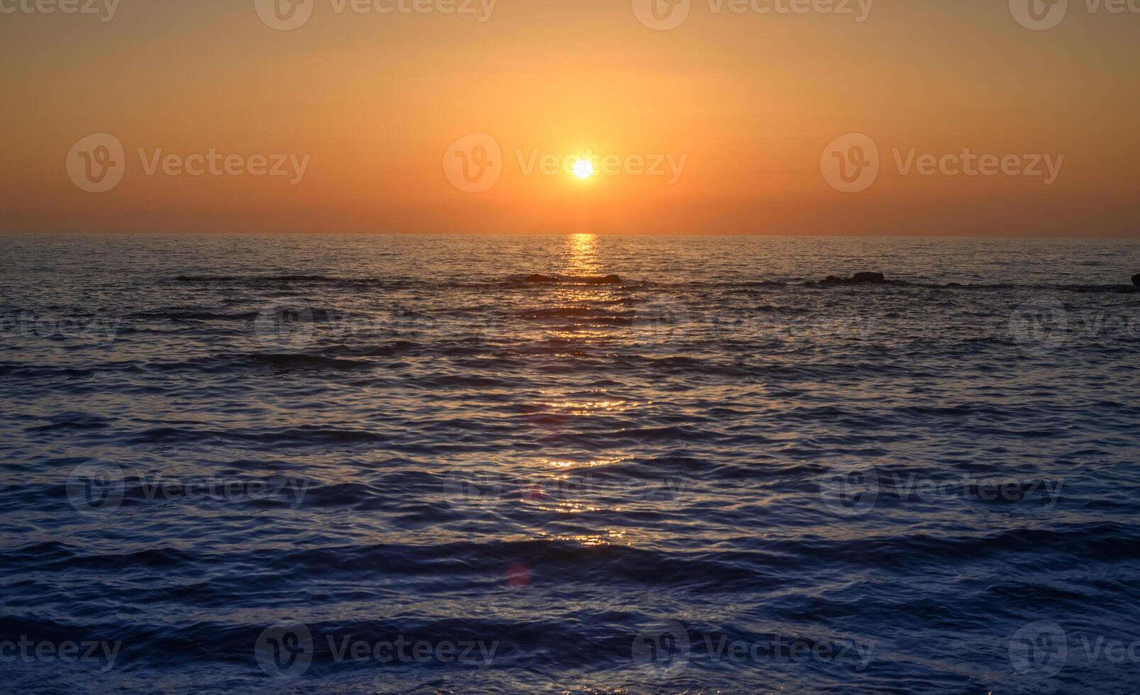 beautiful golden sunset or sunrise on a seashore bank with blue sea water and yellow sunnny evening cloudy sky photo