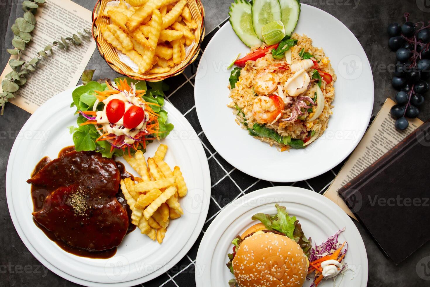 Seafood Fried Rice, Chicken Steak with barbeque sauce, Beef egg and cheese burger, french fries served on plate isolated on table top view of assorted asian food photo