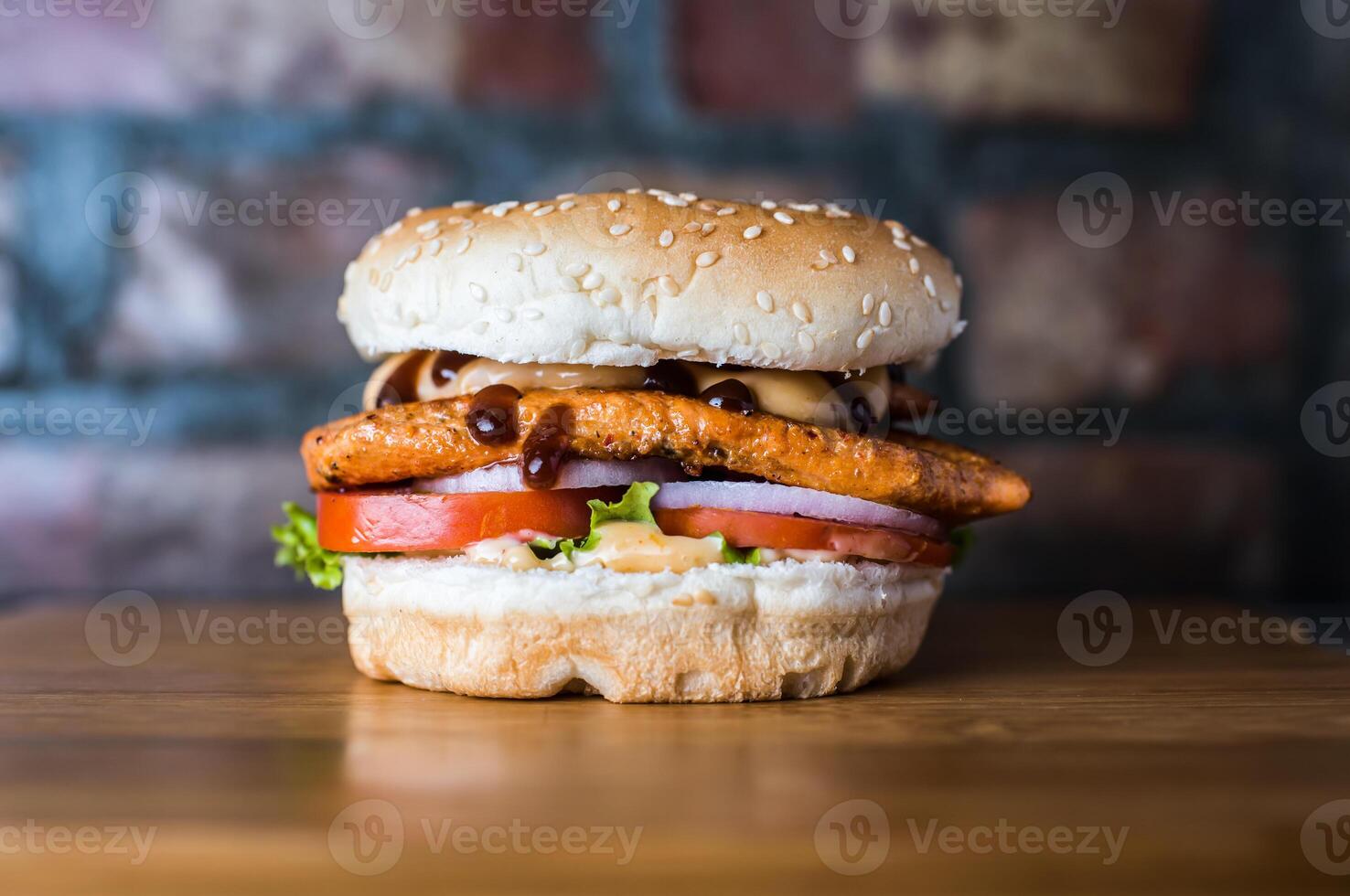 Grilled Chicken Burger include chicken patty, mayonnaise, lettuce leaf, tomato and onion isolated on wooden board side view of unhealthy junk fastfood photo