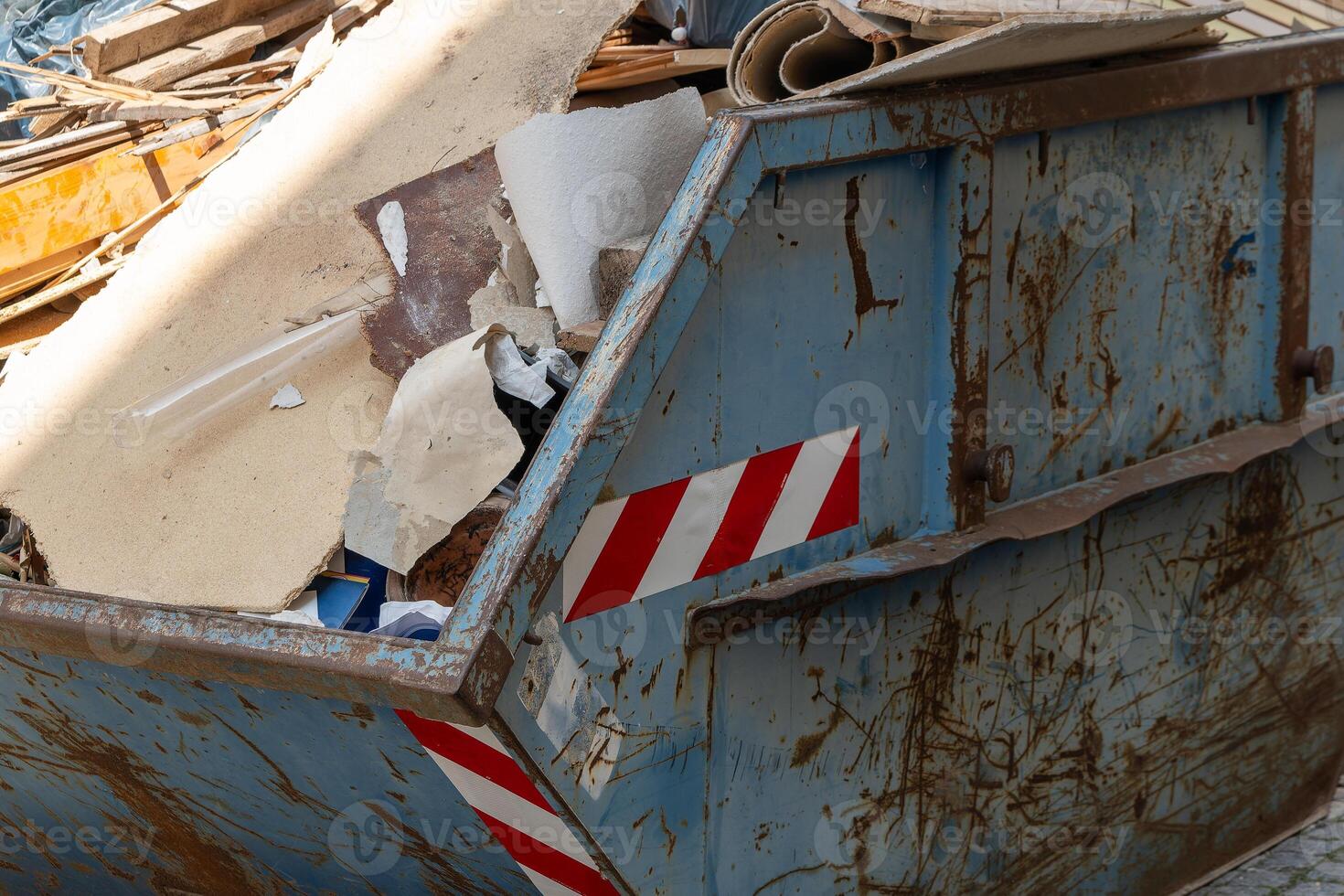 dumpster is full of trash and has a red and white striped sticker on it photo