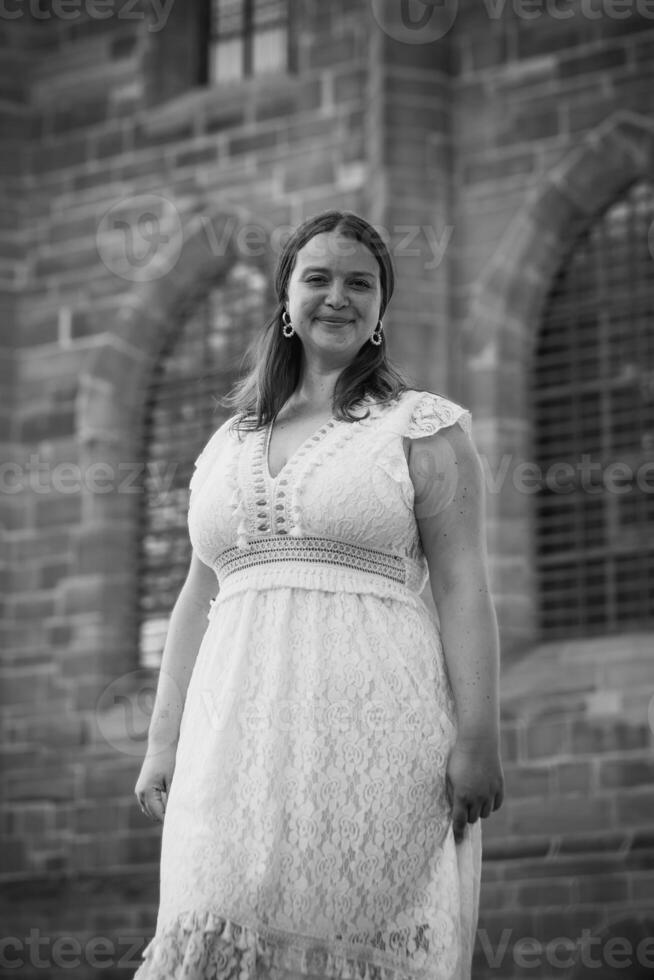 woman in a white dress stands in front of a building photo