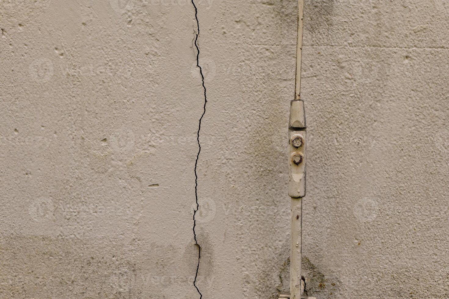 crack in a wall with a bolt sticking out of it photo