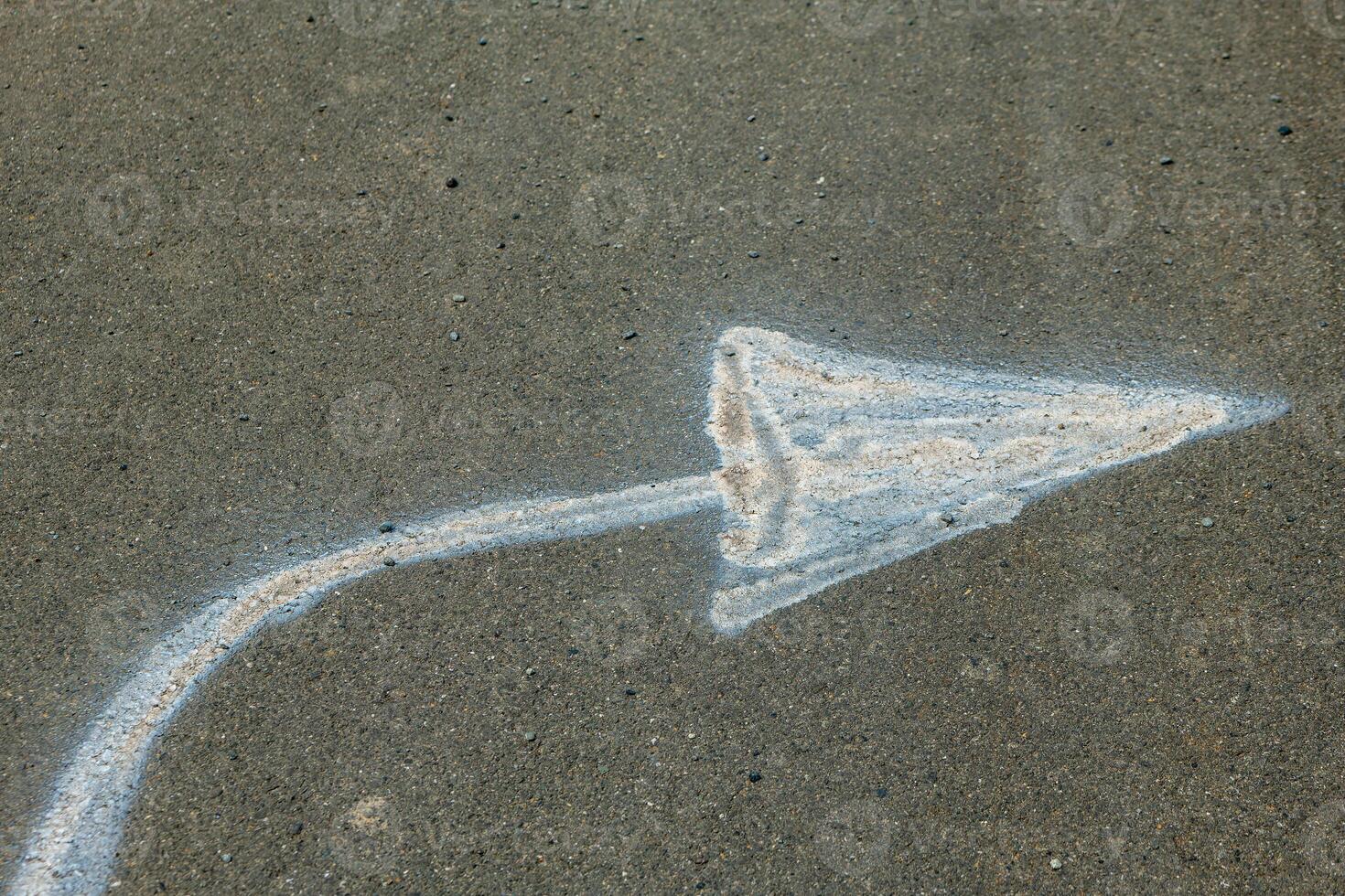 white arrow is drawn on a grey concrete surface photo