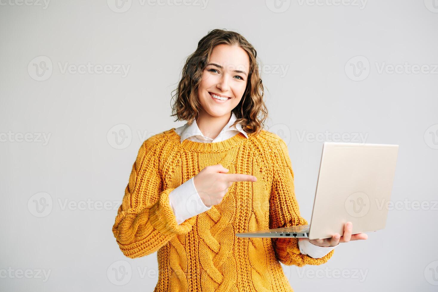 Young Woman Presenting E-Learning on Laptop. Cheerful female student pointing at a laptop screen, promoting e-learning courses and educational software. Ideal for online education concepts. photo
