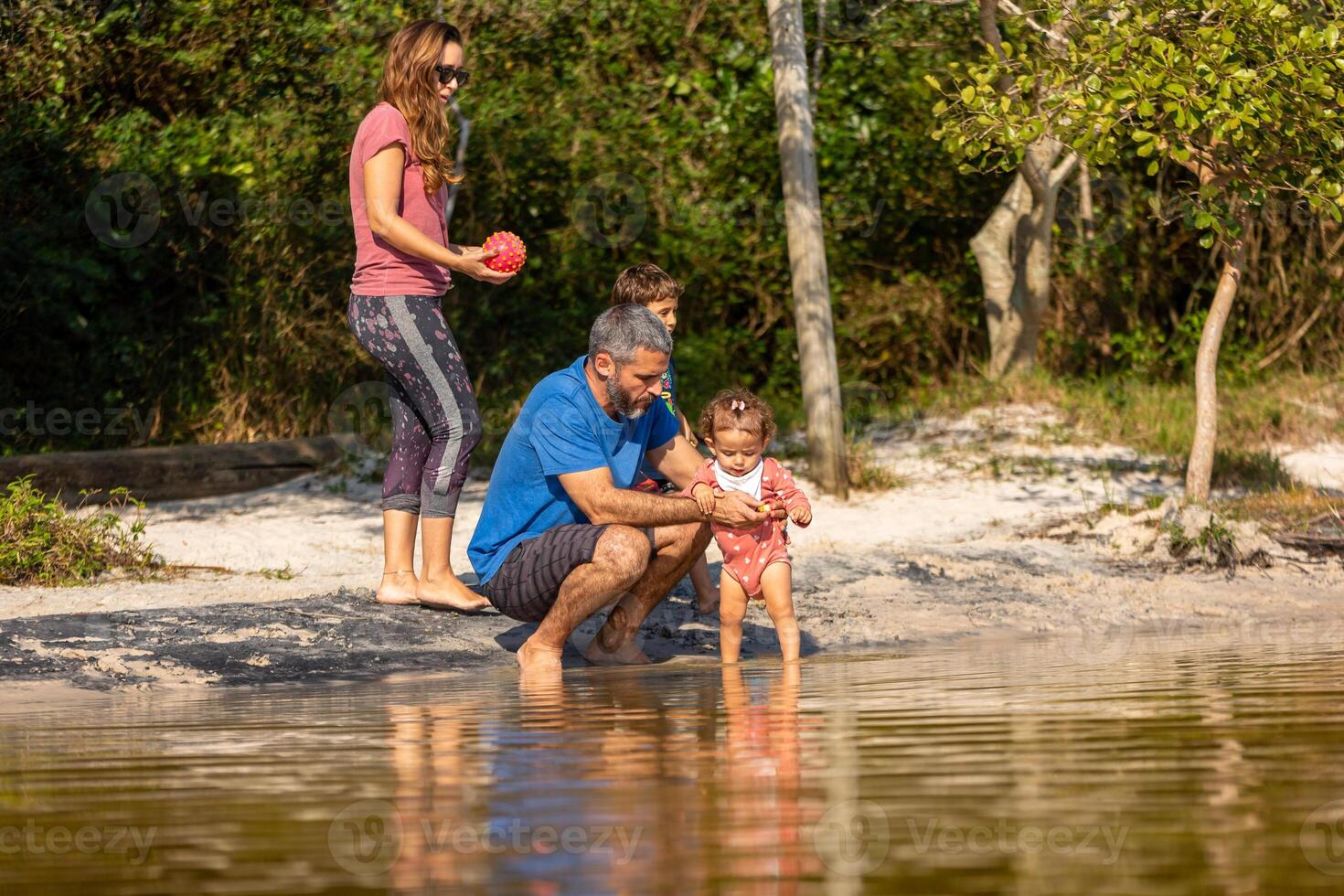 Young caucasian family having a picnic at the lake on a sunny afternoon. photo
