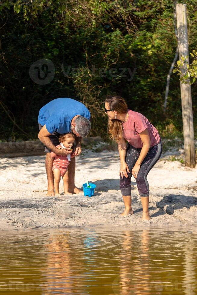 Young caucasian family having a picnic at the lake on a sunny afternoon. photo
