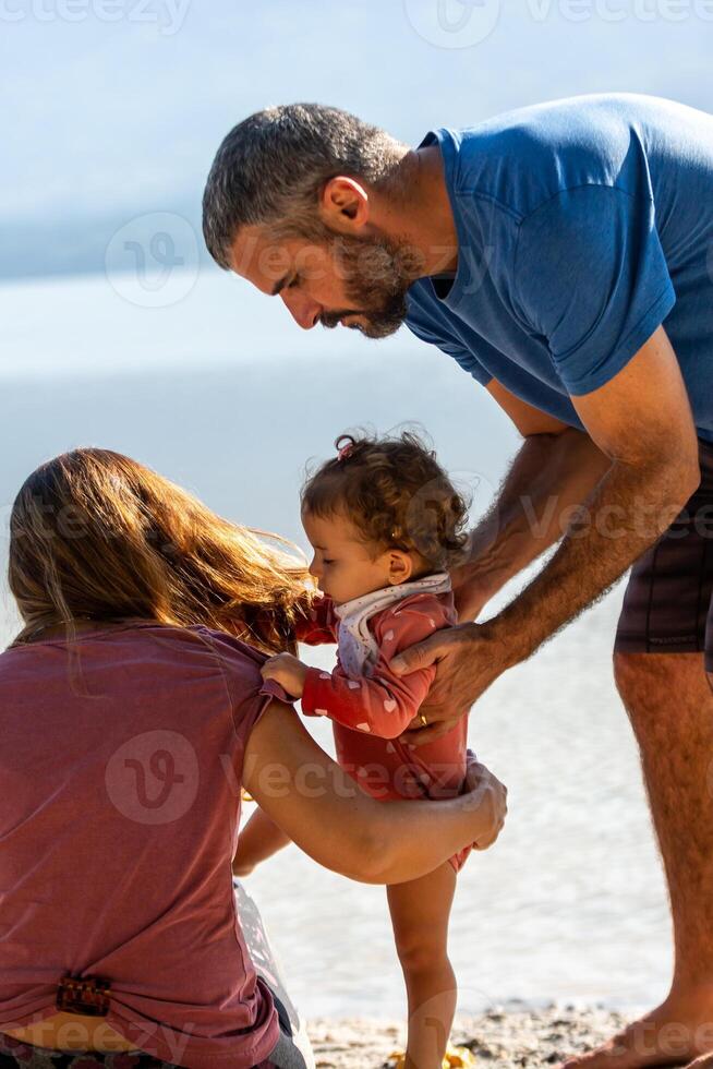 Young caucasian family having a picnic at the lake on a sunny afternoon. photo