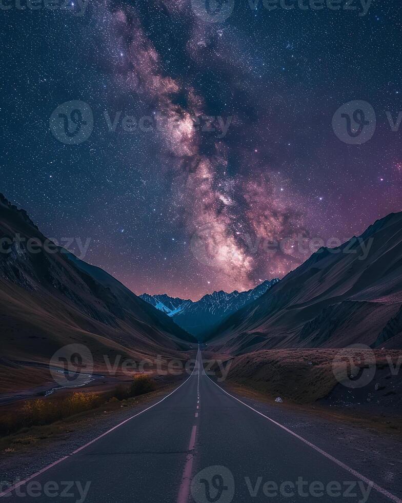 Road leading to distance in mountain valley, breathtaking view of a starry night sky over a desolate road surrounded by mountains photo