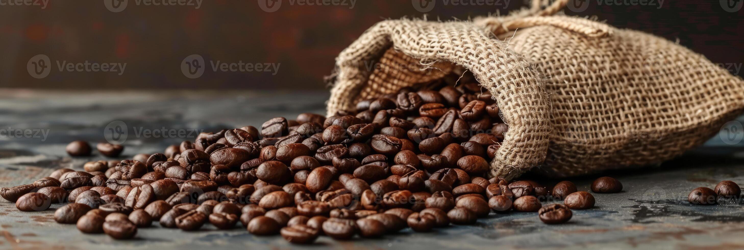 Roast coffee beans spilled out of a burlap sack onto a black table on dark background photo