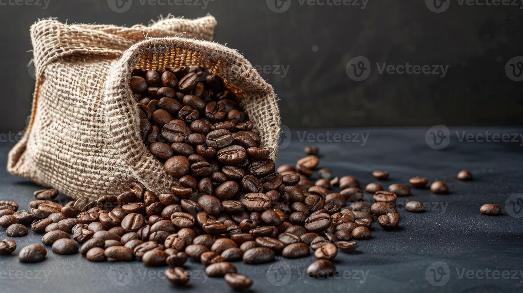 Roast coffee beans spilled out of a burlap sack onto a black table on dark background photo