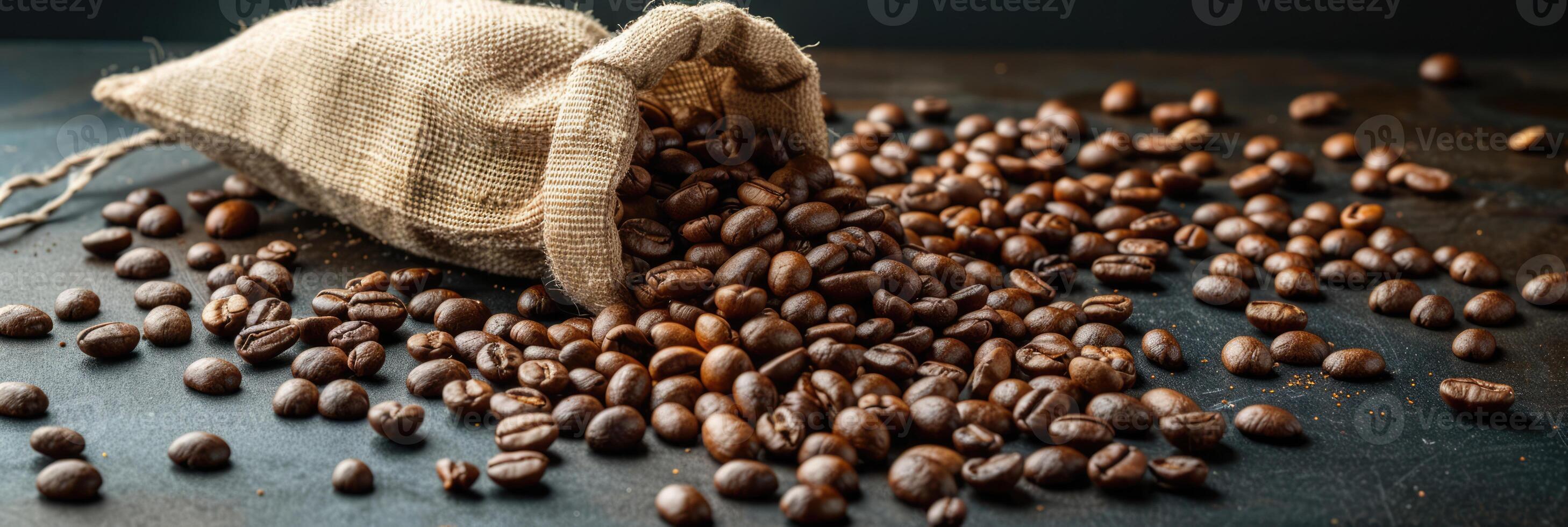 Roast coffee beans spilled out of a burlap sack onto a black table on dark background photo