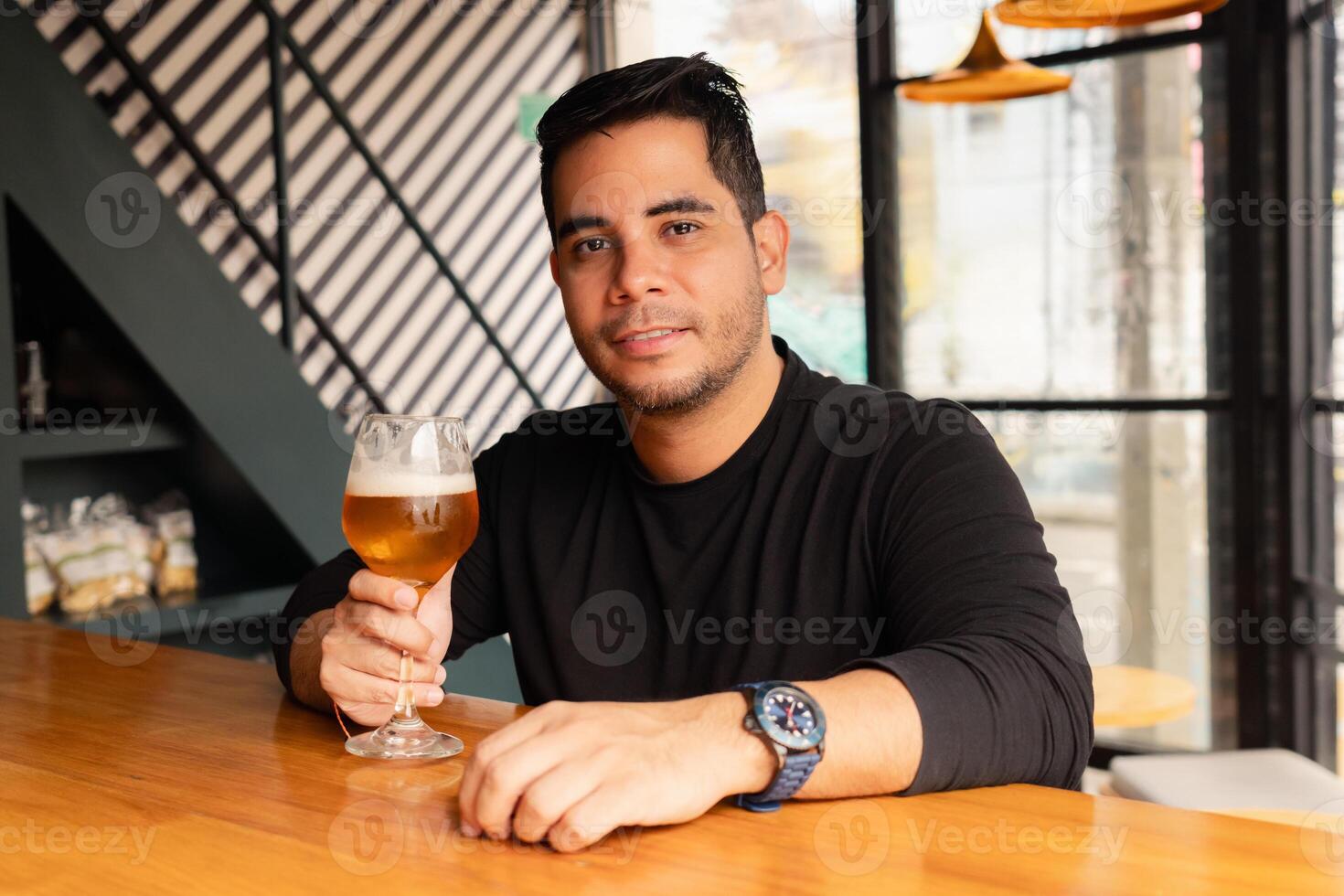 Smiling man looking at camera with a beer at the bar in a modern bar with stylish interior. photo