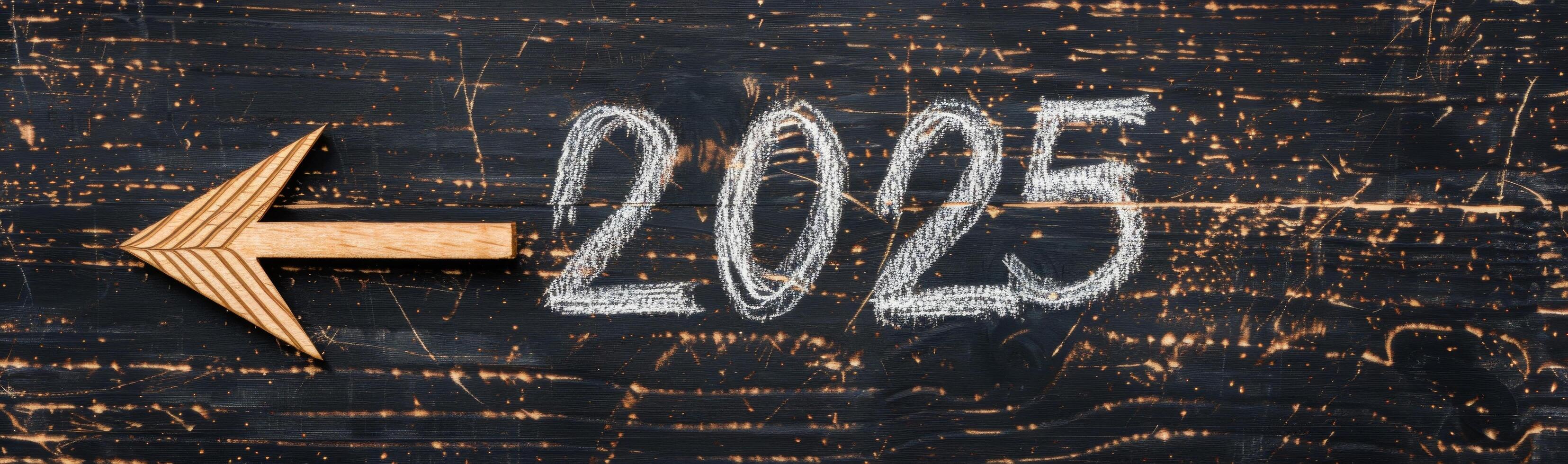 Wooden Arrow Pointing Left Towards 2025 on a Weathered Chalkboard Surface photo