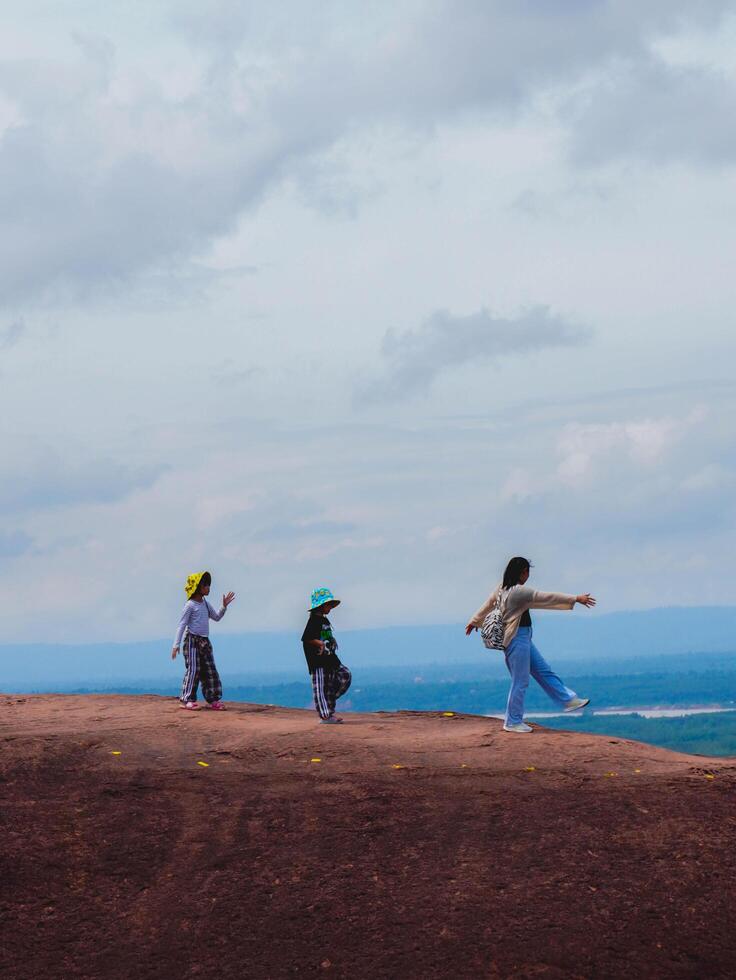 Adventurers stand on a large boulder in the middle of a forest in a national park, Three Whale Rock or Hin Sam Whales in Buegkan province, Thailand. photo