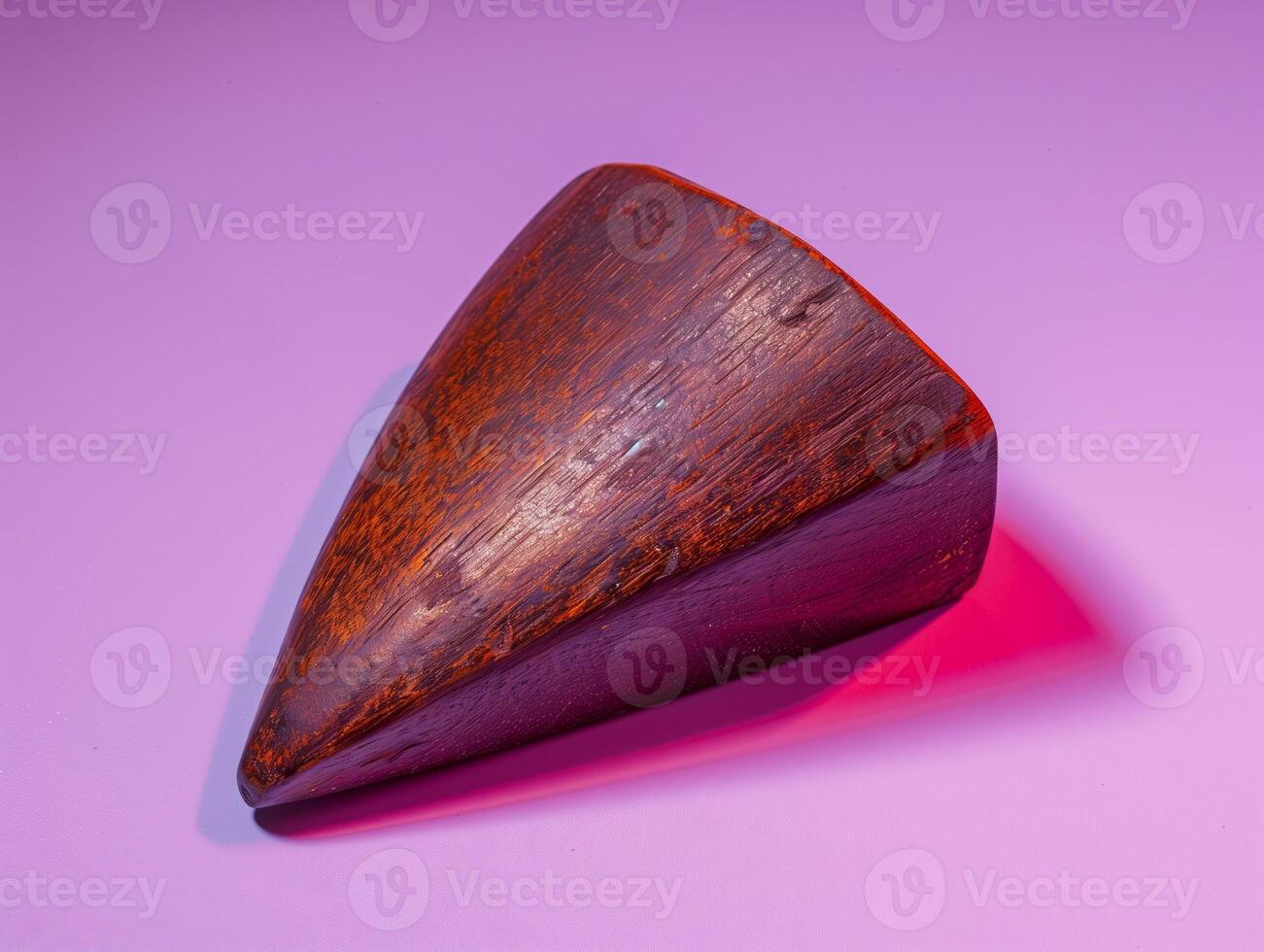 Wooden triangular object on purple background. photo