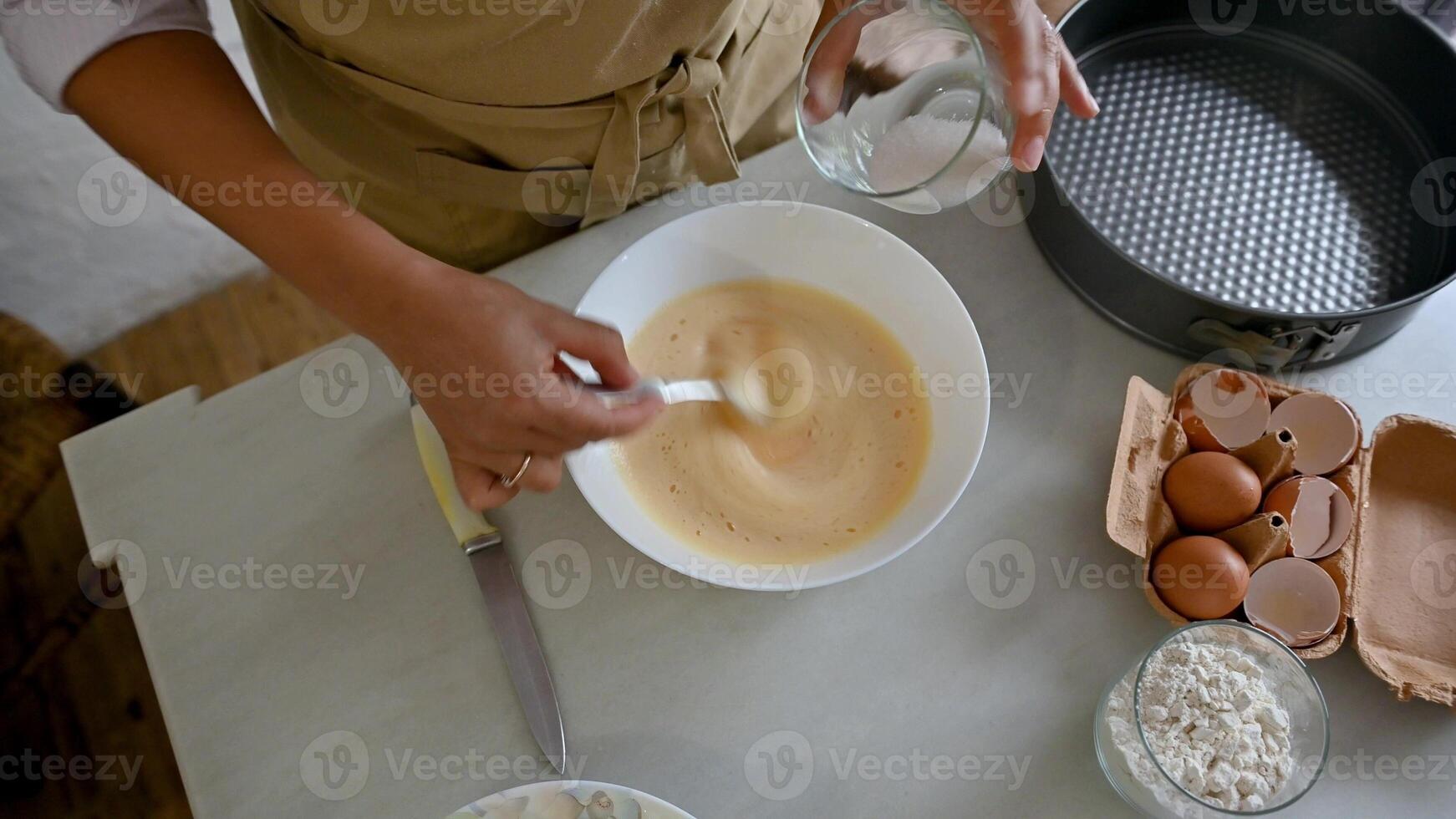 Woman preparing apple pie batter in a white bowl on a kitchen counter photo