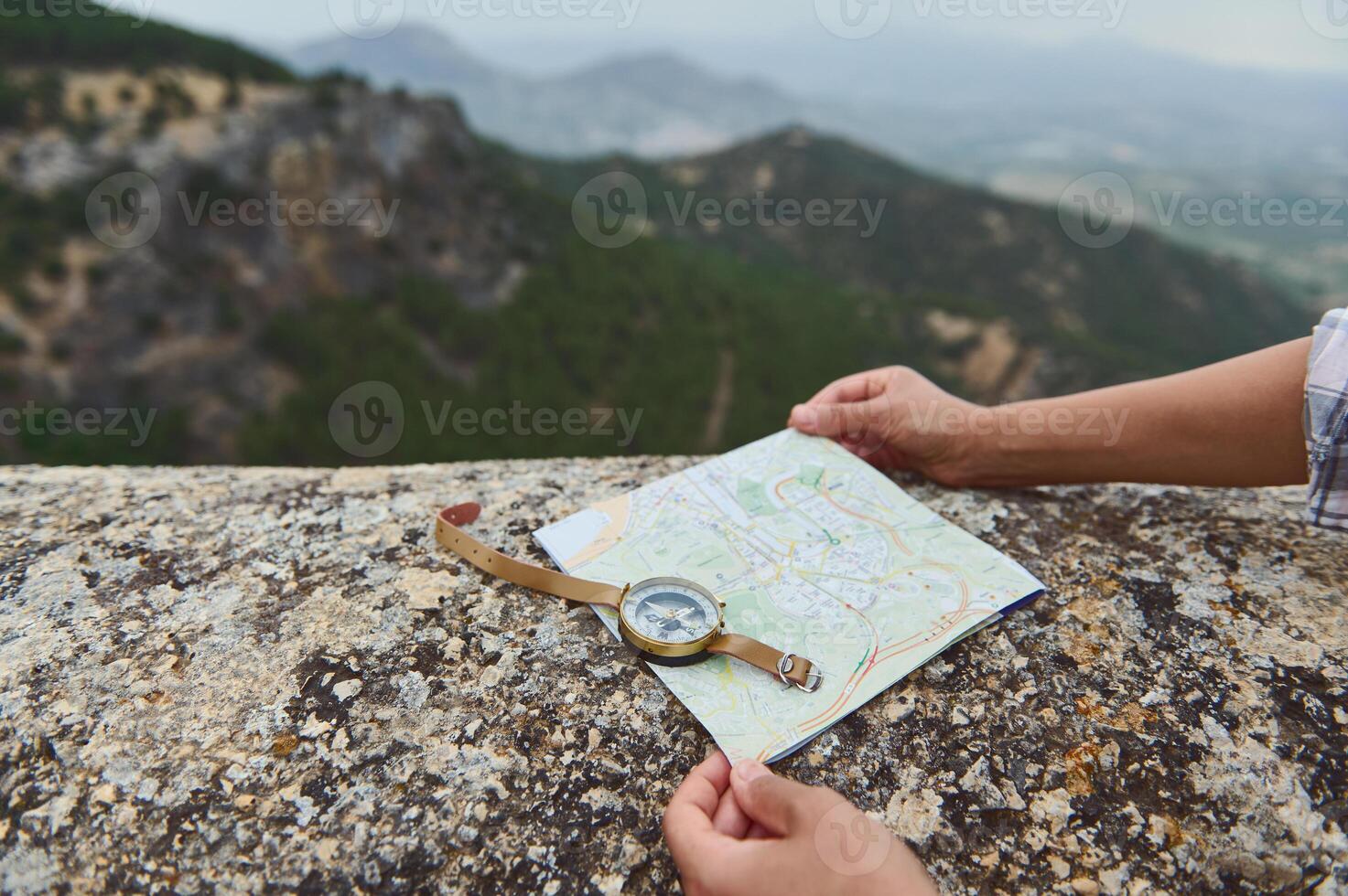 Traveler navigates with map and compass on a mountainous trail with scenic view photo
