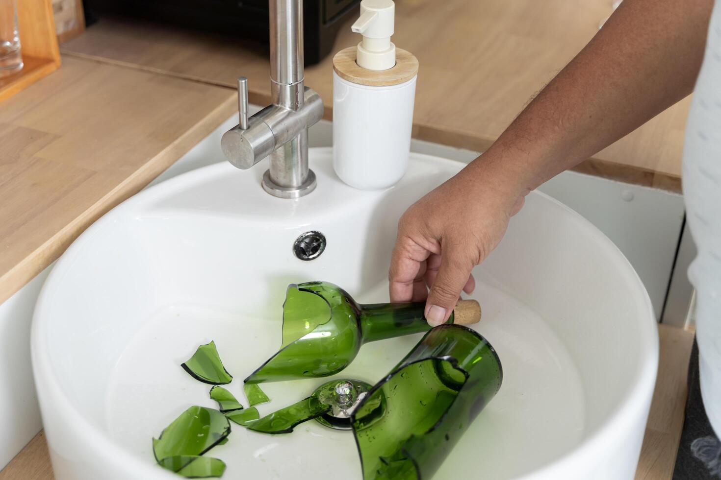 Broken green glass bottle inside white sink in modern kitchen.Broken glass bottle looks dangerous. photo