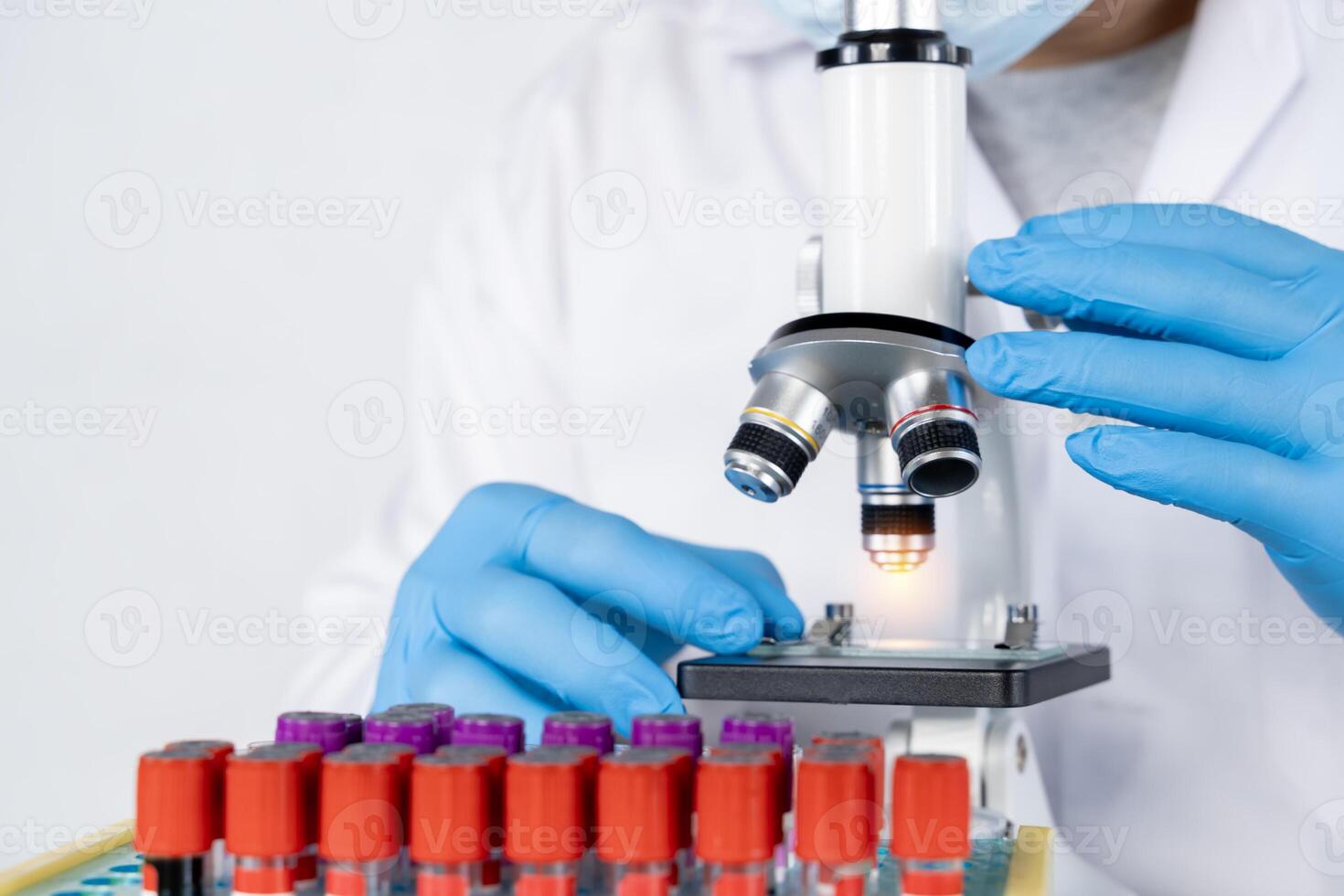 Doctor hand taking a blood sample tube from a rack with machines of analysis in the lab background. photo