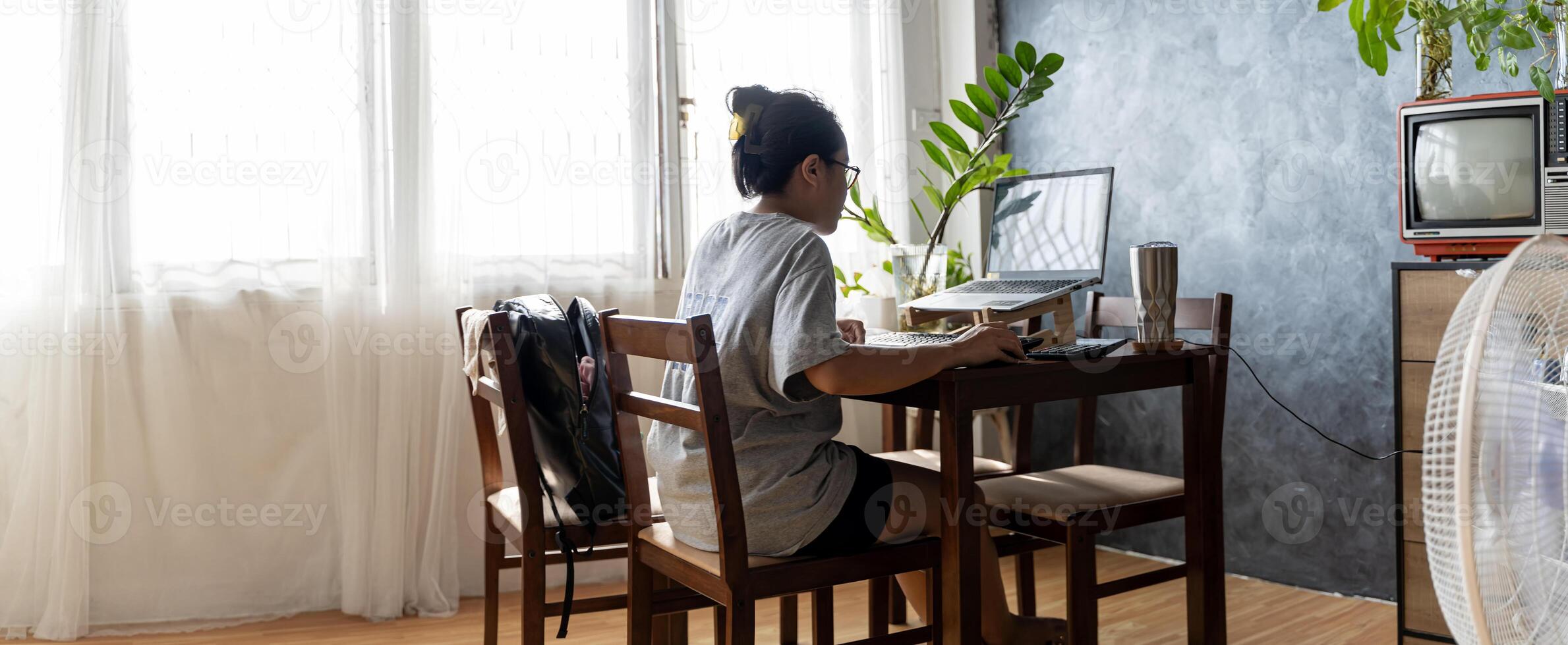 Professional businesswoman working at her home on laptop, young female manager using mobile computer device while sitting at dining table. photo