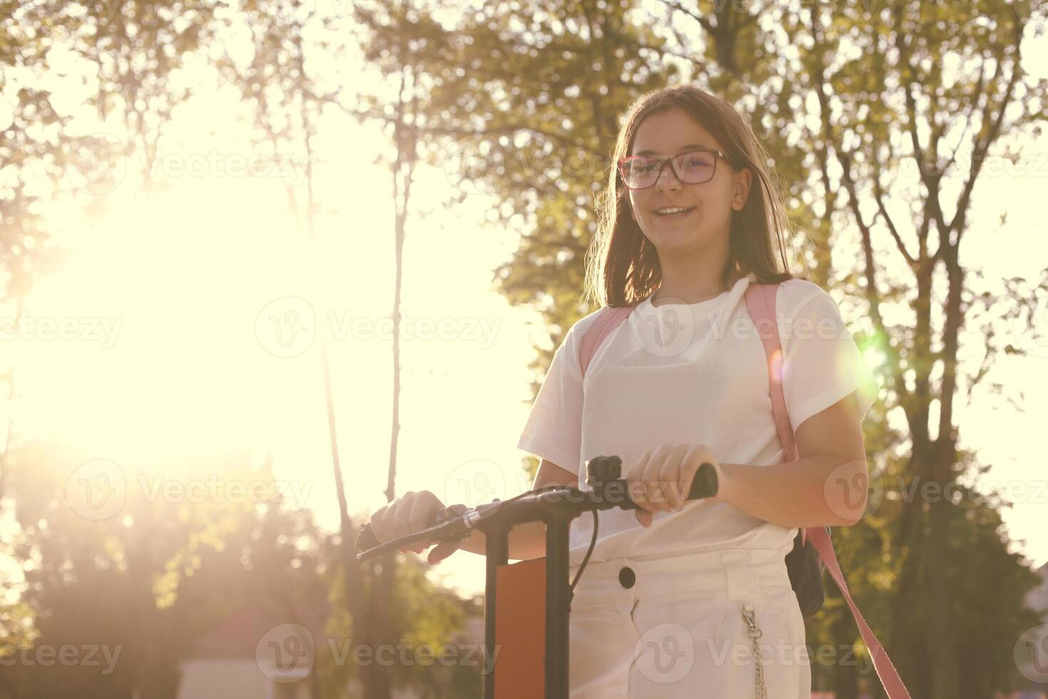 Pretty young smiling girl student riding blue electric kick scooter photo