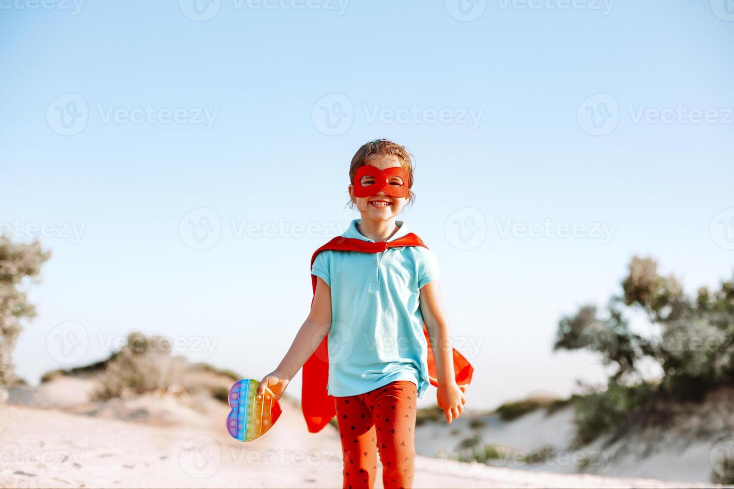 Superhero kid playing with flexible toy the Pop It fidget outdoors photo