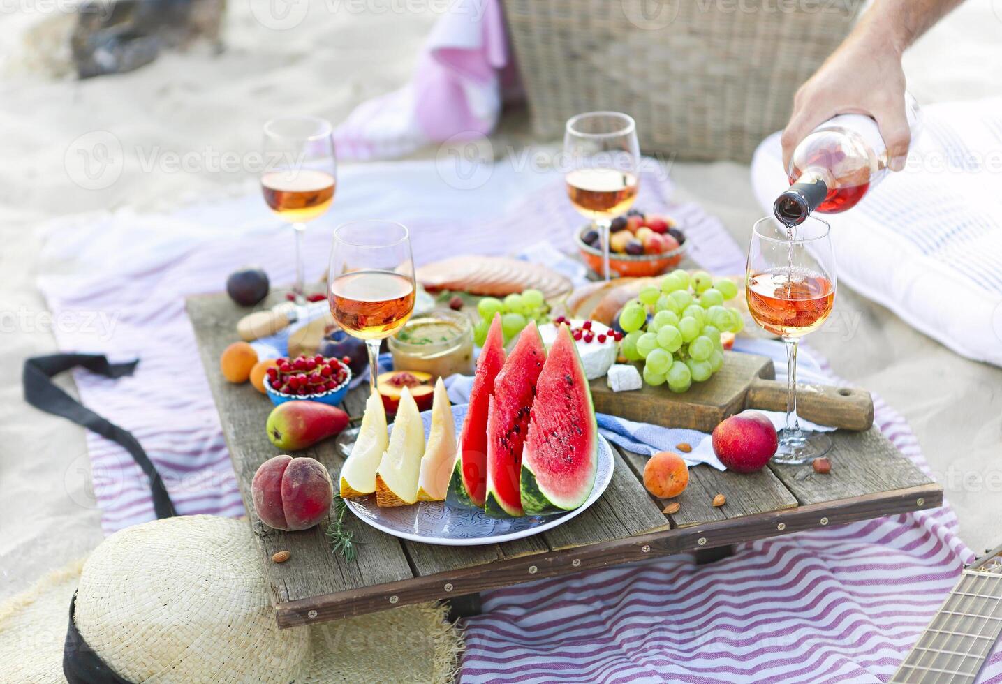 Man pouring wine having picnic on beach photo