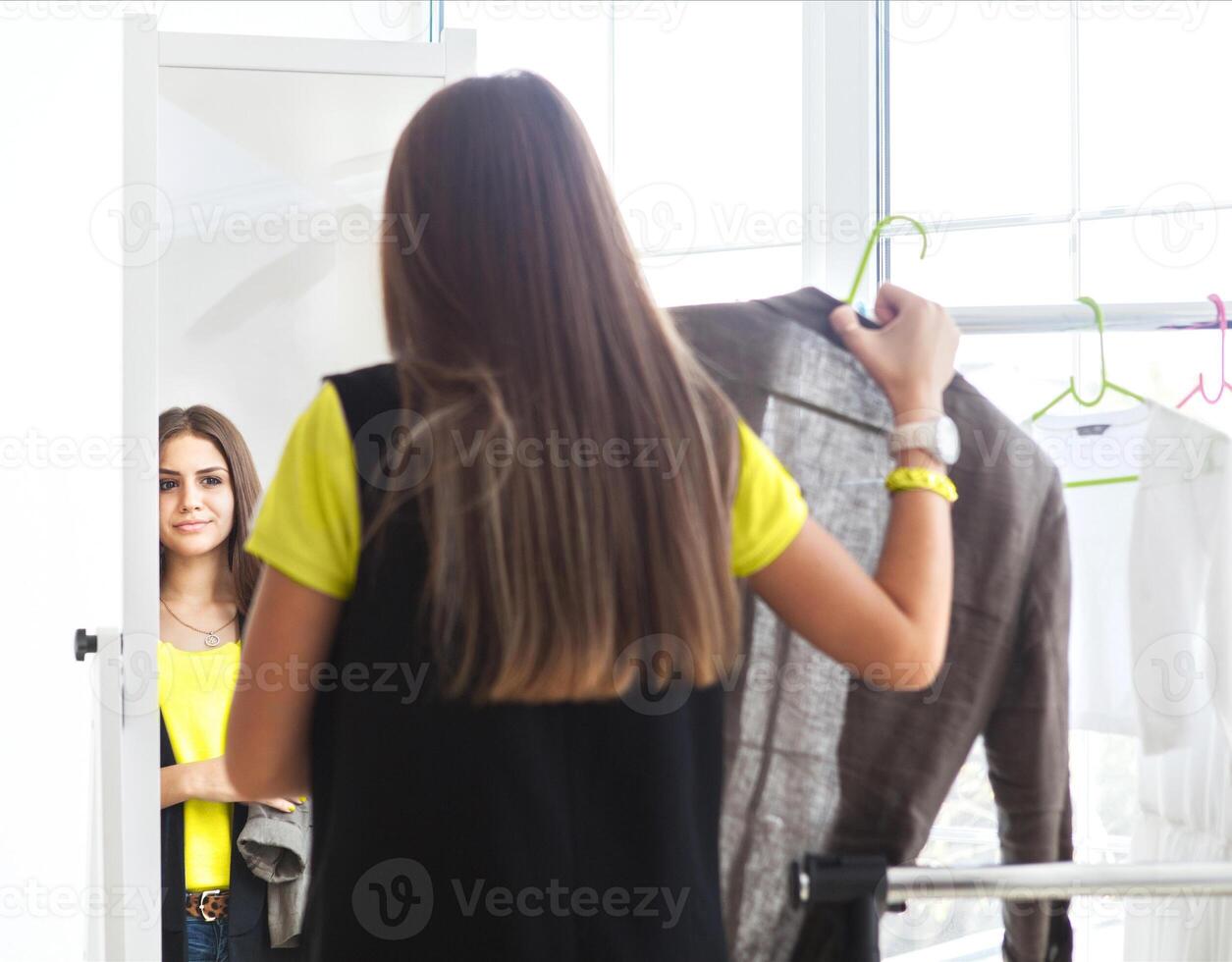 Portrait of attractive teen girl making choices clothes at home photo