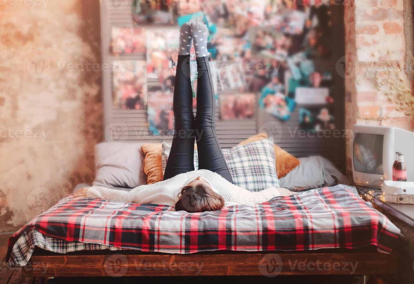 Young woman resting on bed against retro posters photo