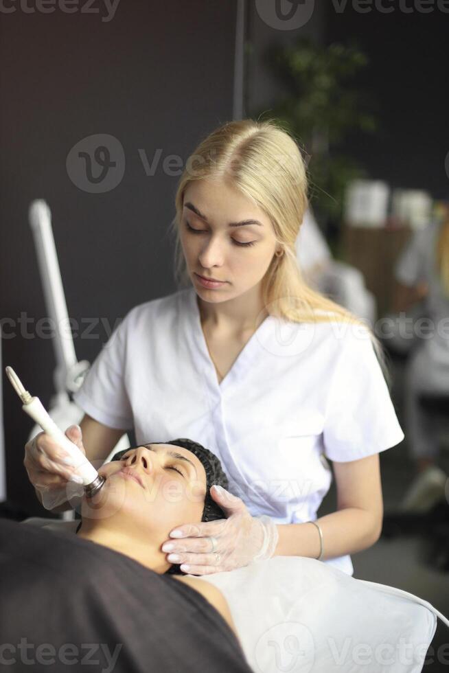 Beautician using machine for radiofrequency lifting photo